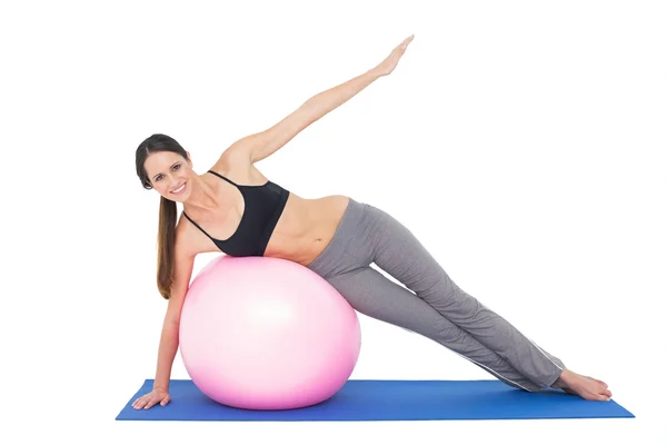 Lunghezza completa di una donna in forma che si estende sulla palla fitness — Foto Stock