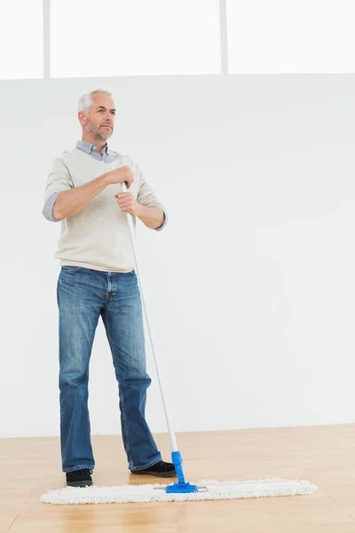 Longitud completa de un hombre maduro reflexivo de pie con una fregona —  Fotos de Stock