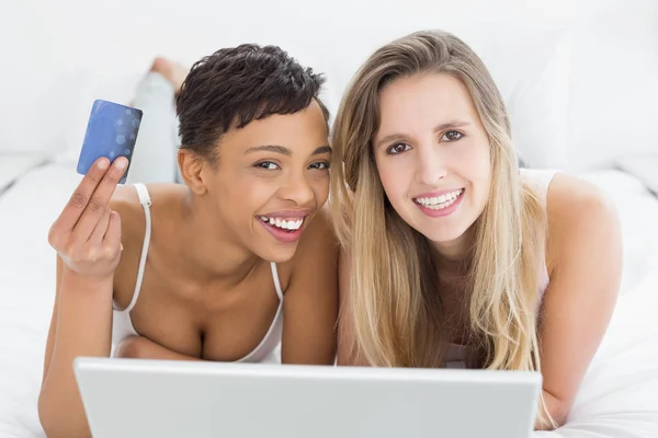 Happy relaxed female friends doing online shopping in bed — Stock Photo, Image