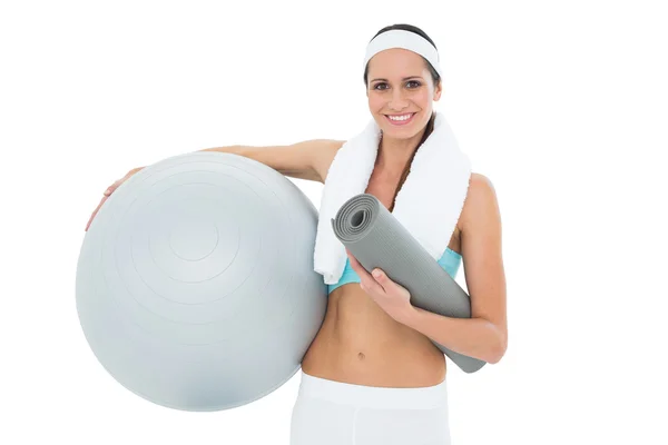 Sonriente mujer en forma sosteniendo la pelota de fitness y la estera — Foto de Stock