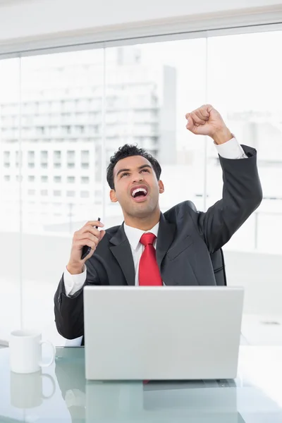 Businessman cheering in front of laptop at desk — ストック写真