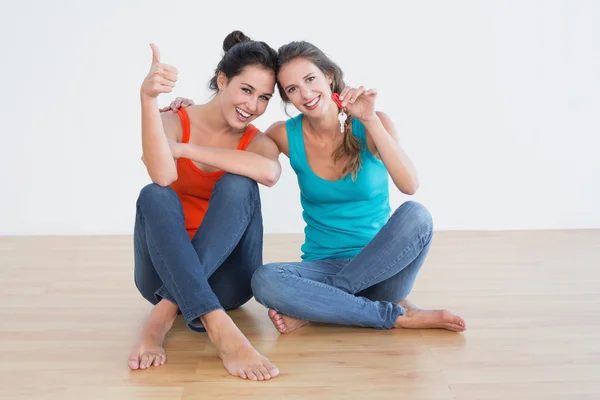Friends gesturing thumbs up with keys on the floor — Stock Photo, Image