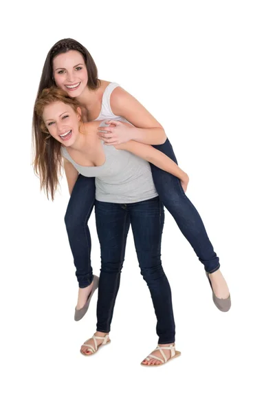 Volledige lengte portret van een jonge vrouwelijke piggybacking vriend — Stockfoto