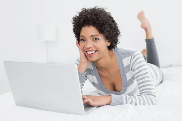 Mujer bastante joven usando el ordenador portátil en la cama — Foto de Stock