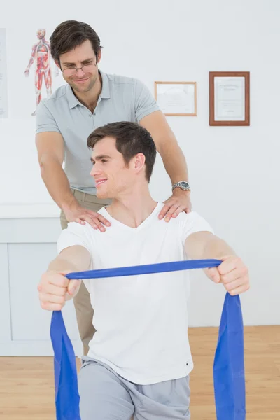 Mannelijke therapeut helpen man met oefeningen in office — Stockfoto