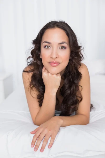 Portret van een mooie brunette liggend in bed — Stockfoto