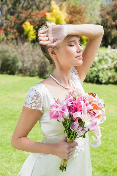 Schöne blonde Braut hält Arm an Stirn — Stockfoto