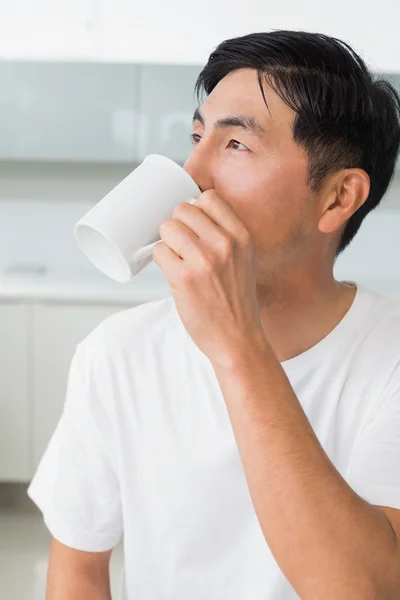 Uomo serio che beve caffè mentre distoglie lo sguardo in cucina — Foto Stock