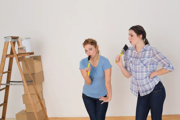 Vrienden zingen in verfborstels door ladder in een nieuw huis — Stockfoto