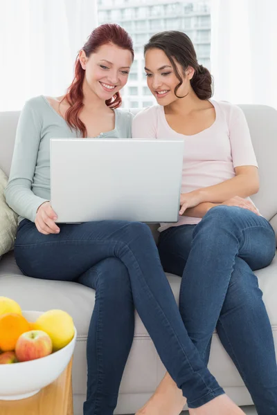 Avslappnad unga kvinnliga vänner använder laptop hemma — Stockfoto