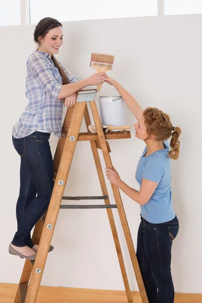 Amici con pennello e lattina sulla scala in una nuova casa — Foto Stock