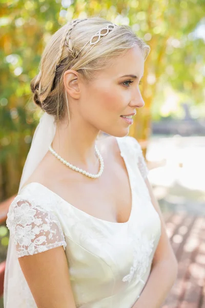 Hübsch lächelnde blonde Braut steht auf einer Brücke — Stockfoto