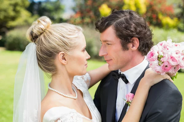 Bride and groom embracing and smiling at each other — Stock Photo, Image