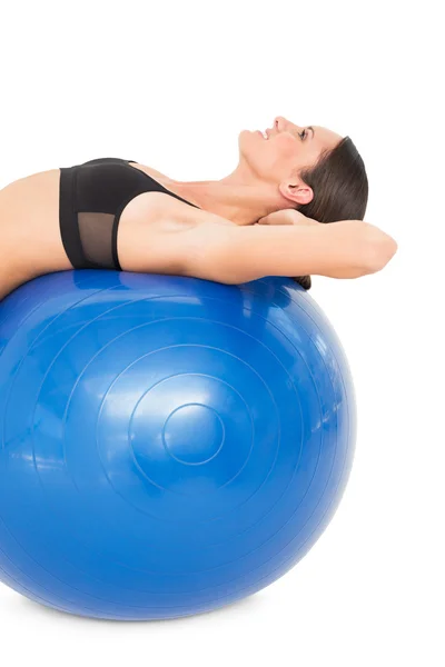 Vista lateral de una mujer en forma estirándose en la pelota de fitness —  Fotos de Stock