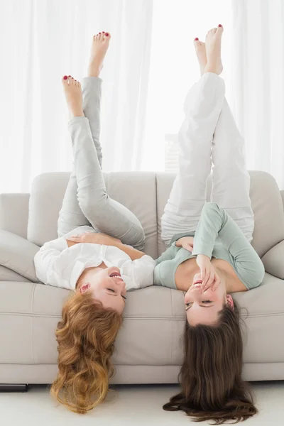 リビング ルームで空気中の足のソファに横たわっている女性の友人 — ストック写真