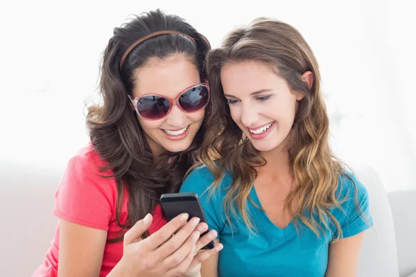 Female friends in sunglasses reading text message — Stock Photo, Image