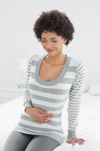 Donna casual con mal di stomaco seduta a letto — Foto Stock