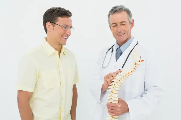 Médico mostrando paciente algo en esqueleto modelo — Foto de Stock