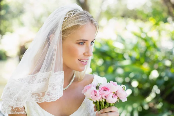 Gelukkige bruid in een sluier houden haar boeket — Stockfoto