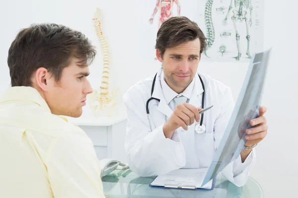 Médico que explica a radiografia da coluna vertebral ao paciente no consultório — Fotografia de Stock