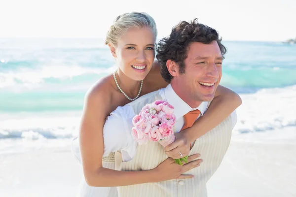 Handsome groom giving his new wife a piggy back — Stock Photo, Image