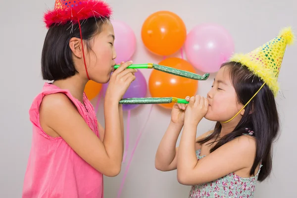 Girls blowing noisemakers at a birthday party — Stock Photo, Image