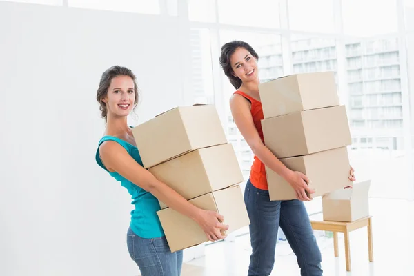 Female friends carrying boxes in in new house — Stock Photo, Image