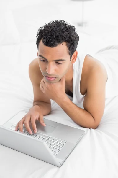 Casual man met laptop in bed — Stockfoto