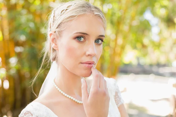 Hübsche blonde Braut steht auf einer Brücke und schaut weg — Stockfoto