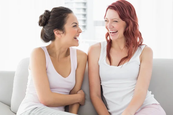 Vackra kvinnliga vänner skrattar i vardagsrummet Stockfoto