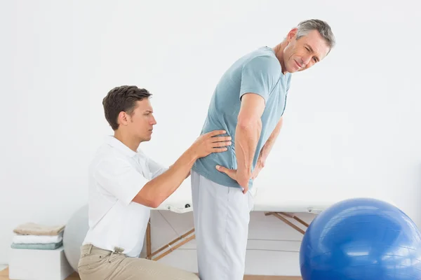 Therapist massaging mans lower back in gym hospital Royalty Free Stock Images