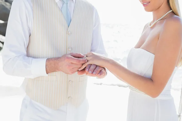 Man placing ring on brides finger Stock Photo