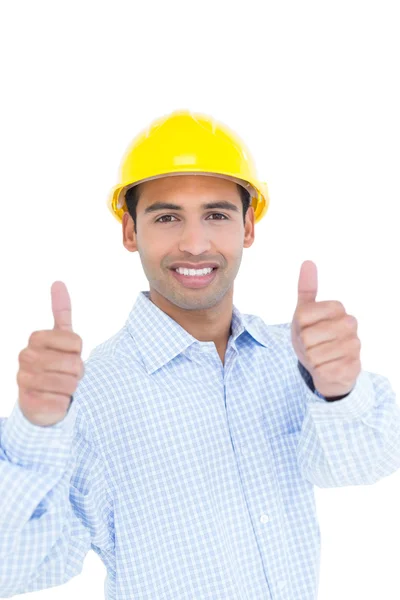 Smiling handyman in yellow hard hat gesturing thumbs up Stock Photo