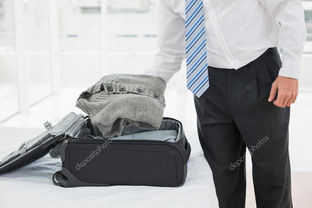 Mid section of a businessman unpacking luggage