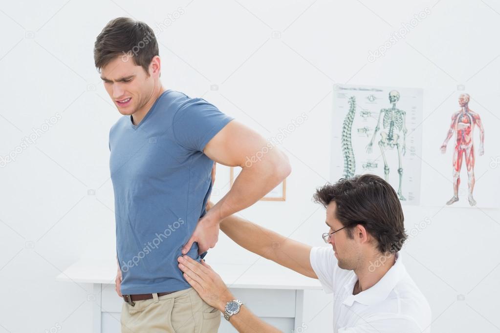 Mid section of a physiotherapist examining mans back