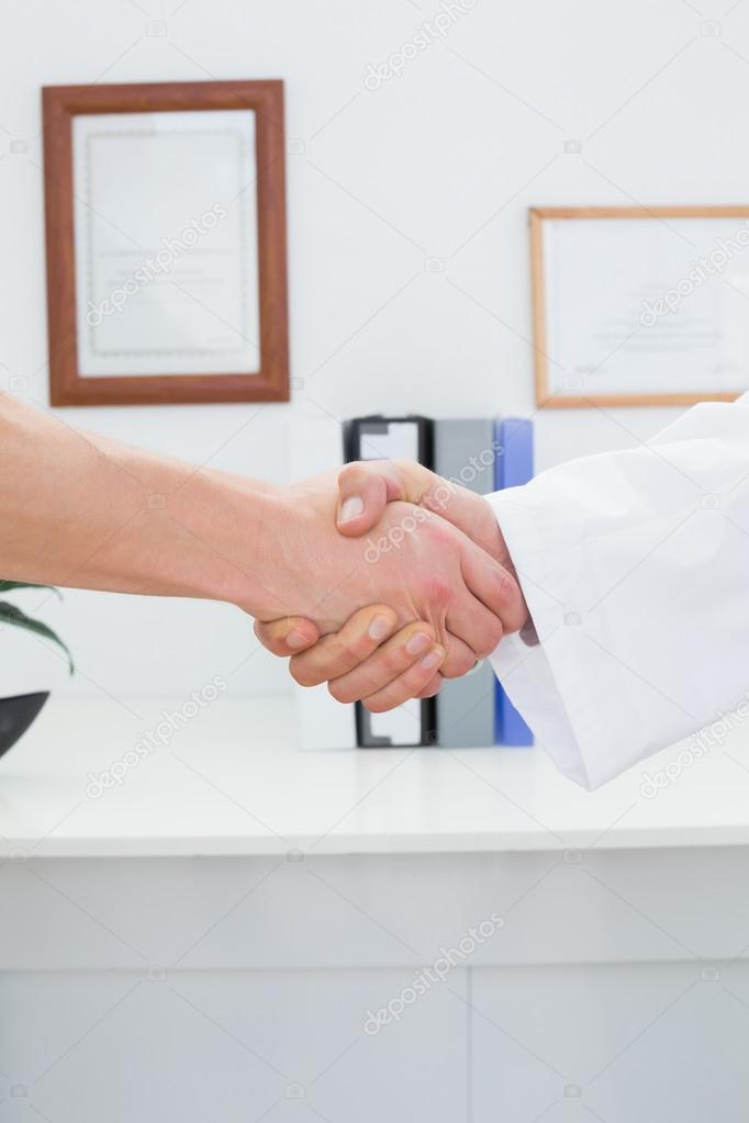 Close-up mid section of a doctor and patient shaking hands