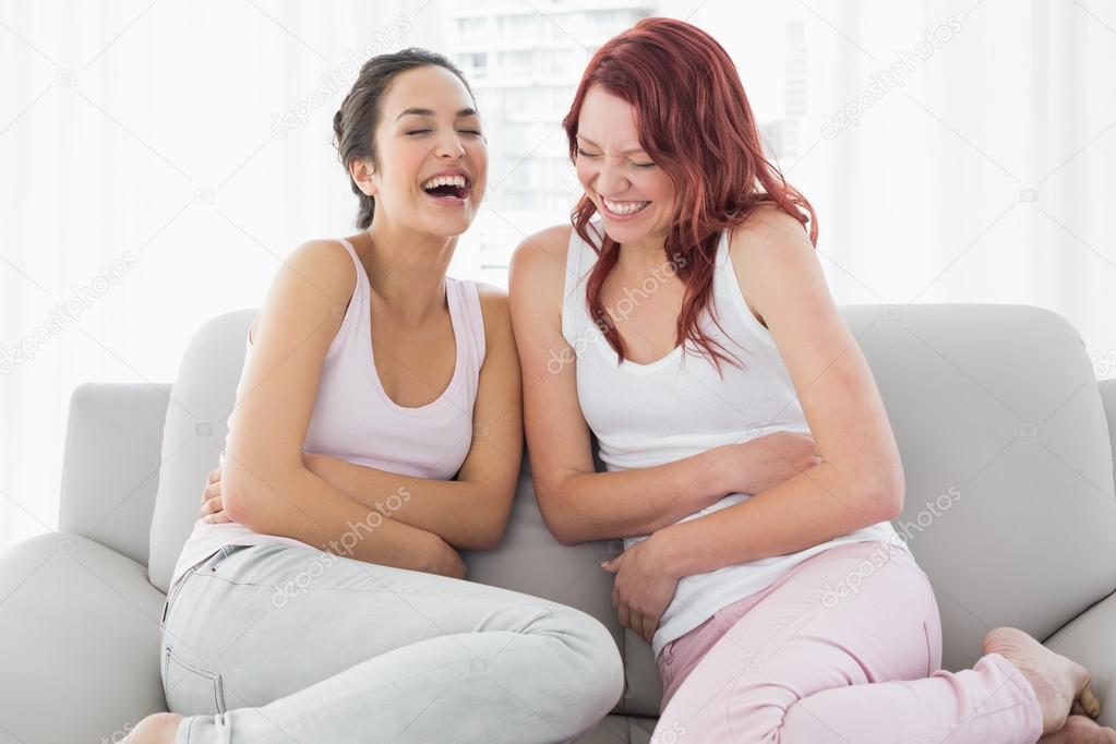 Two beautiful young female friends laughing in living room