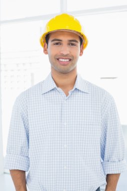 Sarı baret takmış gülümseyen bir tamirciyle portresi