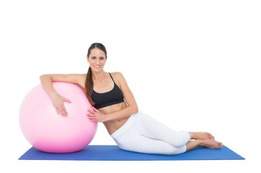 gülümseyen fit fitness topu ile oturan genç kadın