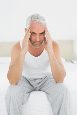 yatakta baş ağrısı çeken adam