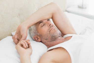 evde yatakta uyuyan olgun adam