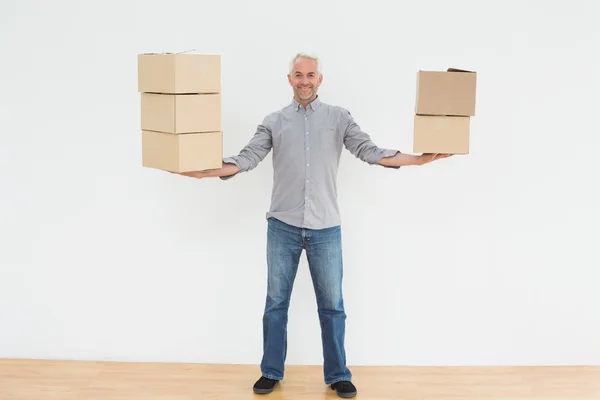 Smiling mature man carrying boxes in a new house — Stock Photo, Image