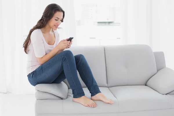 Relaxado mulher mensagens de texto no sofá em casa — Fotografia de Stock