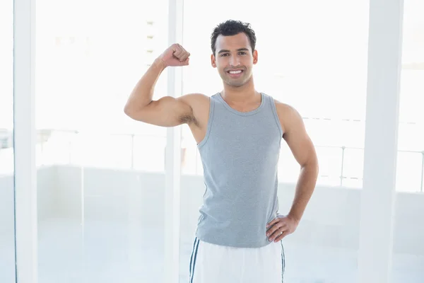 Passar ung man flexar muskler i gymmet — Stockfoto