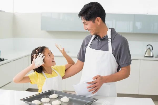 Веселая девушка с отцом готовит печенье на кухне — стоковое фото