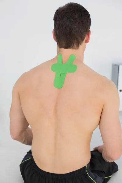 Rear view of a shirtless man with green kinesio tape on back — Stock Photo, Image