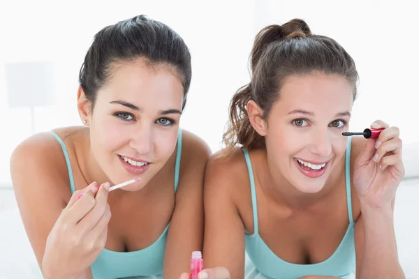 Two young female friends applying make-up in bed — Stock Photo, Image