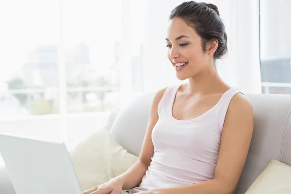 Młoda kobieta korzysta z laptopa na kanapie w salonie — Zdjęcie stockowe