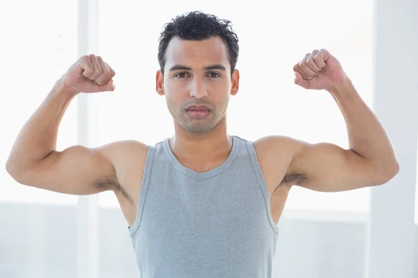 Fitter junger Mann lässt Muskeln im Fitnessstudio spielen — Stockfoto