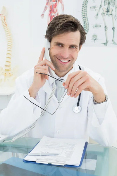 Lachende jonge mannelijke arts via telefoon — Stockfoto